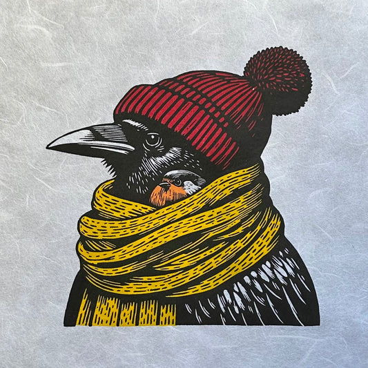 A multicoloured linocut print of a raven wearing a red hat and a yellow scarf, with a little robin nestled under the scarf. This sweet winter scene is a perfect gift for Christmas for bird lovers and art lovers alike. 